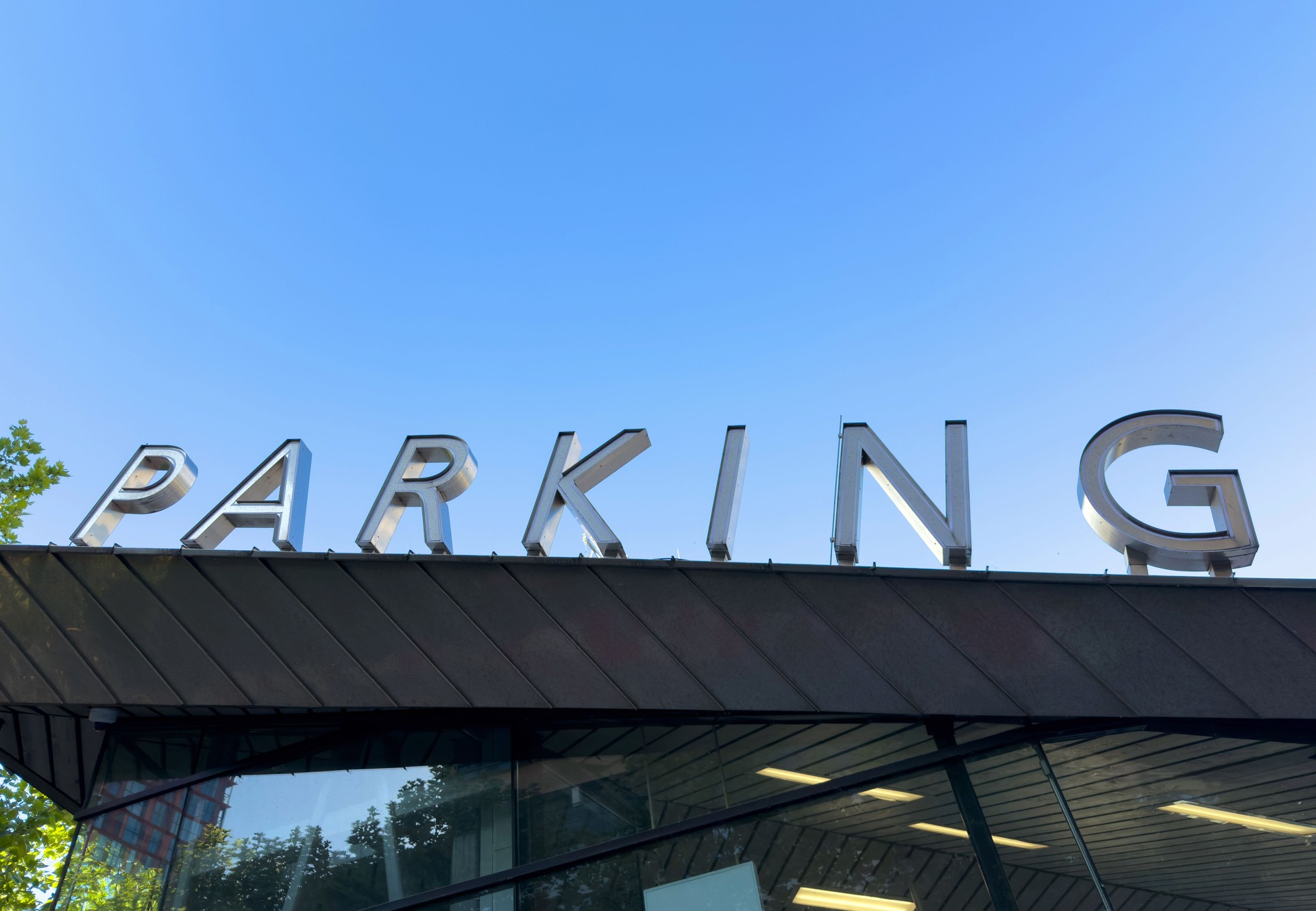 PARKING sign on the roof. Metallic letters text on blue sky background